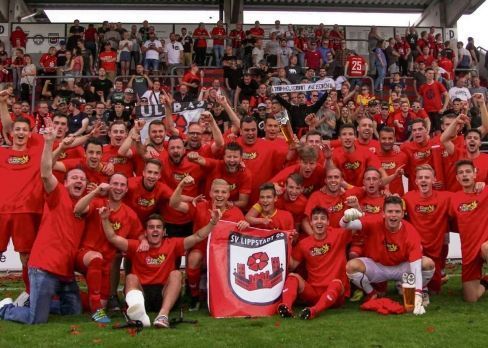 Die Oberliga-Meistermannschaft des SV Lippstadt mit ihren wieder einmal tollen Fans im Hintergrund. Mittendrin der Meistertrainer Daniel Berlinski, und auch der Präsident ließ sich nicht lumpen. In biernassen Klamotten schrie Thilo Altmann (vorn l.) seine